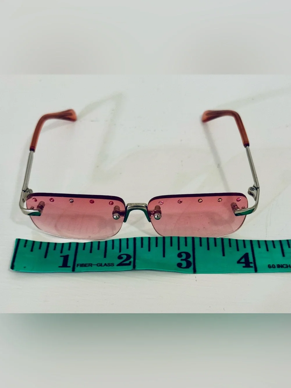 Stylish pink rimless sunglasses adorned with decorative rhinestones. These glass
